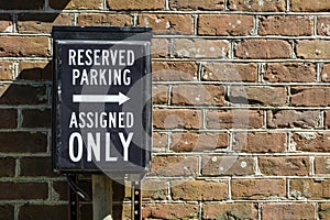 Reserved Parking and Assigned Only sign against a red brick wall