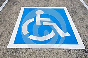 Reserved parking sign for handicapped. Disabled parking space with white blue painted sign of handicapped parking spot