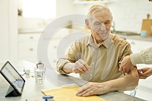 Reserved senior man preparing for blood pressure check