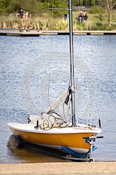 Reservoir small sail boat on clean blue lake water in sunshine on towing trailer sails down