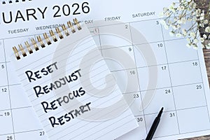 Reset, readjust, refocus, restart, inspirational checklist text in notebook with January 2026 calendar