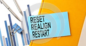 Reset, realign, restart text on sticker on yellow notebook with chart and pen photo