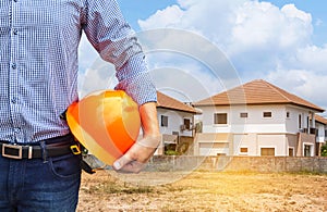 Resident engineer holding yellow safety helmet at new home building