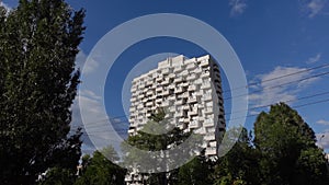 Residential apartment building with balconies on sunny day against blue sky. Urbanistics