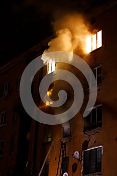 A residential apartment building is on fire at night