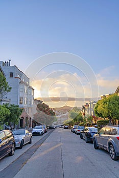 Residential area with roadside parking space and a view of sunset sky in San Francisco, CA