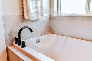 Residential bathroom interior with built in rectangular bathtub beside window