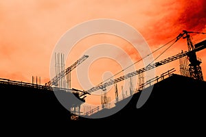 Residential building development and construction, back lit cranes and scaffold