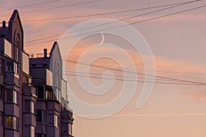 The residential building reflects in the tile and glass a beautiful sunset sky against the backdrop of a growing moon.