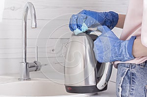 A residential cleaning service worker cleans an electric kettle