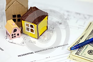 Residential construction agreement ready to sign with small toy houses and pen. Construction contract