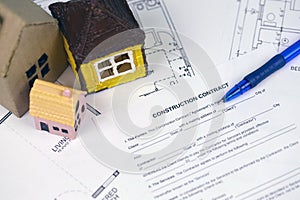 Residential construction agreement ready to sign with small toy houses and pen. Construction contract