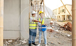 Residential construction workers standing at construction site talking on housing development project using laptop notebook.