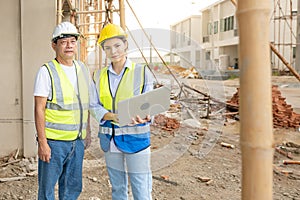 Residential construction workers standing at construction site talking on housing development project using laptop notebook.