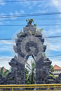 a residential gate in Indonesia that is shaped like an ancient temple with a cable crossing in front of it