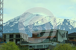 Residential private houses on a hillside above thickets of trees against the backdrop of mountains