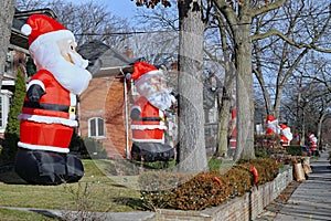 Residential street with a proliferation of giant inflatable Santa Claus dolls