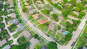 Residential streets with parked cars along row of suburban houses well-trimmed front yard landscape in subdivision suburbs Dallas