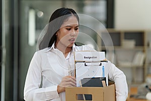 Resignation concept. Fired employee holding box of belongings in an office