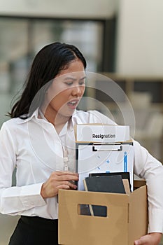 Resignation concept. Fired employee holding box of belongings in an office