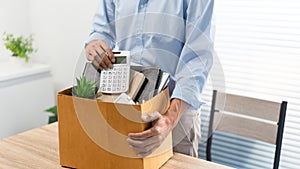 Resignation Concept The man in light blue shirt standing at the desk and putting the calculator and other stuff into the box