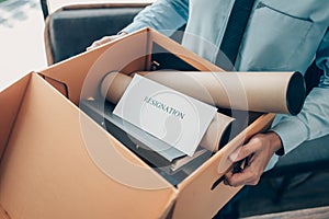 Resignation letter in cardboard box and employee hold box in office. Quiting a job, businessman fired or leave a job concpet