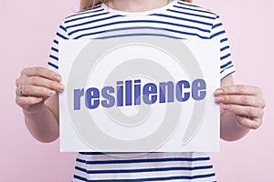 Resilience word concept written under torn paper on white background with woman.
