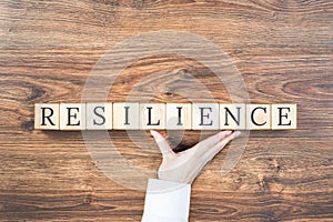 Resilience word on wooden building blocks with supporting hand
