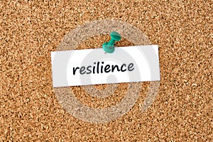 Resilience. Word written on a piece of paper, cork board background