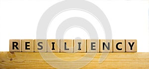 Resiliency symbol. Word `Resiliency` written on wooden blocks. Copy space. Beautiful wooden table, white background. Business an