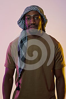 A resilient and charismatic African American man stands against a vibrant yellow gel background, donning a Palestinian