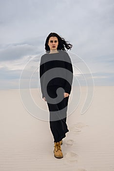 Resolute girl, in black, walks through the desert