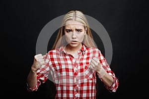 Resolute teenager expressing fierce in the black colored studio