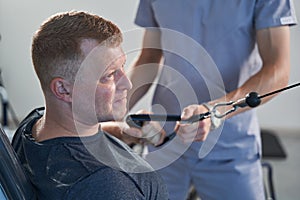 Resolute young man with injury train arm, hand on weight lift machine