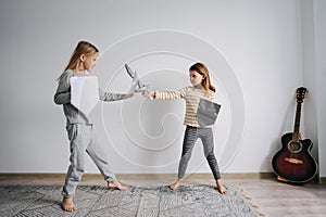 Resolved siblings battling with self-made toy paper swords and shields