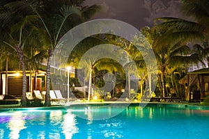 Resort hotel pool at night with lights and palm trees i