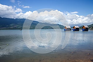 Resort at Lang Co Lake in Vietnam with huts and mountains in the background under a cloudy blue sky