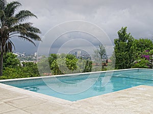 Resort pool overlooking San Jose, Costa Rica skyline against storm clouds.