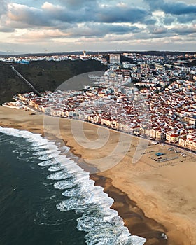 Resort town by the sea or ocean with a clean beach without people, summer cloudy, Nazare Portugal