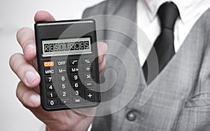 RESOURCES word text inscription on calculator in a male hand of a businessman in white shirt and blue tie, Concept of finance and