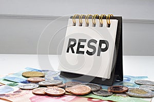 RESP letters on notebook with coins and bills on a clear background