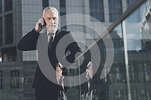 A respectable man with a beard in a business suit talking on the phone