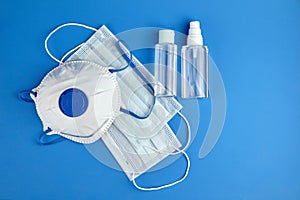 Respirator FFP2, bottles of antibacterial hand sanitizer alcohol antiseptic gel and surgical masks on blue background