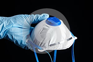 Respirator FFP2 in hand in blue rubber glove, isolated on black background