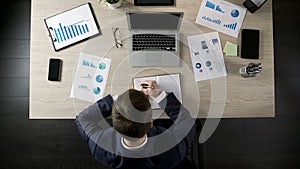 Responsible businessman writing in notebook, making to-do list, time management