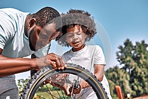 Responsible father fixing a flat tyre of his son bike