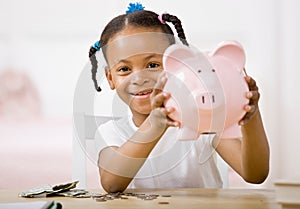 Responsible girl putting money into piggy bank photo