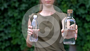 Responsible lady choosing reusable glass bottle instead of plastic, save planet