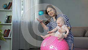 Responsible mother doing early development exercises with active baby girl