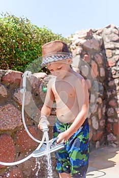 Responsible young boy rinsing off his shoes